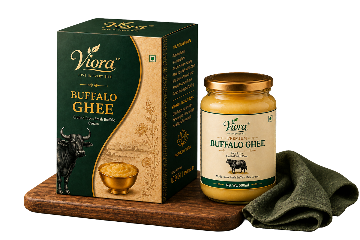 Viora Premium Buffalo Ghee 500ml jar and its green and gold packaging box, displayed on a wooden block with an olive green cloth on a white background.